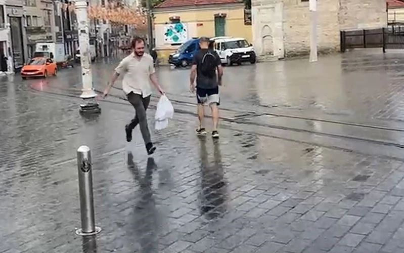 Taksim’de yağmur etkili oldu: Bir vatandaş yağmurdan kartonla korundu